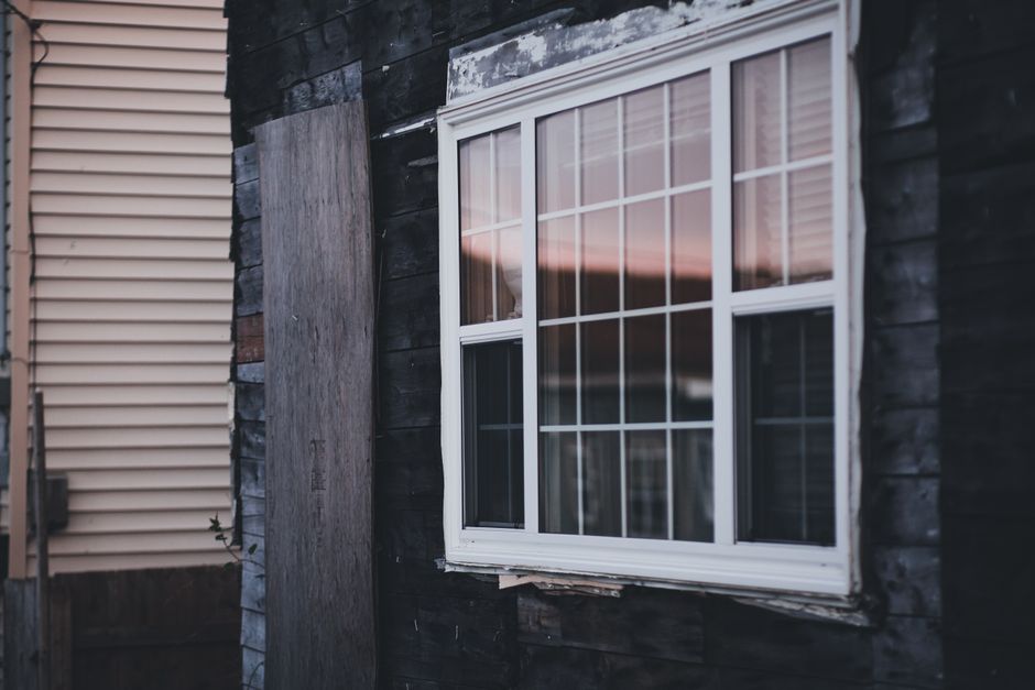 A wooden house facade with a window reflecting the evening sky, showcasing rustic charm.